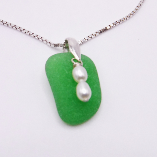 Piece of jade green sea glass with fresh water pearls floating on top of the sea glass and attached to the pendant with a sterling silver bail.